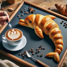 there is a croissant shaped like a fish on a tray next to a cup of coffee