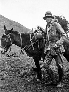 an old photo of a man standing next to a horse