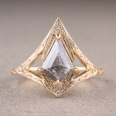 a yellow gold ring with a white diamond in the center and an intricate band around it