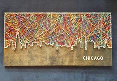 the chicago skyline string art is displayed on a wooden plaque that reads,'chicago '