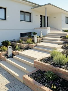 a house with steps leading up to the front door and landscaping around it, including plants