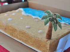 a decorated cake in the shape of a beach with a palm tree on top and white pebbles around it