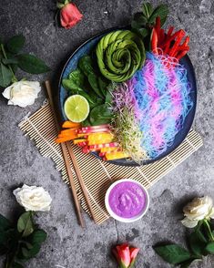 a plate filled with vegetables and dips next to flowers