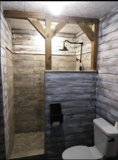 a bathroom with a toilet, shower and wooden paneled walls on the side of it