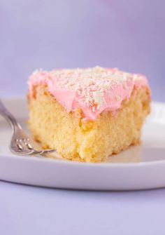 a piece of cake with pink frosting on a white plate next to a fork