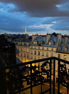 the city skyline is lit up at night, with buildings in the foreground and dark clouds overhead