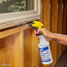 a person is holding a spray bottle and spraying it on the side of a house