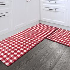 a red and white checkered tablecloth is on the floor in front of cabinets