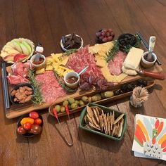 an assortment of meats and cheeses on a wooden platter with olives