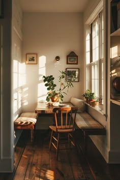 the sun shines through two windows into a dining room with wooden chairs and table