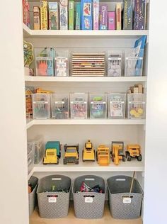 the shelves are filled with plastic bins and toy trucks, books, and other toys