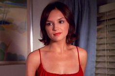 a woman in a red dress is looking at the camera with an intense look on her face