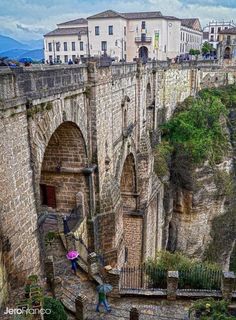 people are walking up and down the stairs in an old castle like area with stone walls