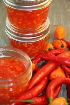 several jars filled with red peppers sitting on top of a table