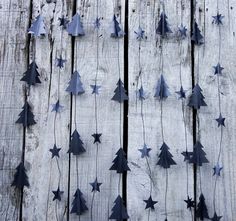 blue paper christmas trees are hanging on a wooden fence