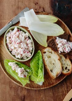 a wooden plate topped with bread and salad