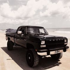 a black truck parked on top of a sandy beach