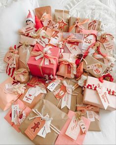 a pile of brown and pink gift bags on top of a white bed covered in tags