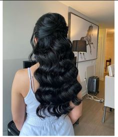 the back of a woman's head with long, wavy black hair in a ponytail