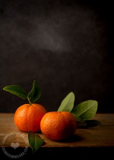 two oranges sitting on top of a wooden table