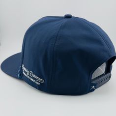 a blue hat with white lettering on the front and side, sitting on top of a table