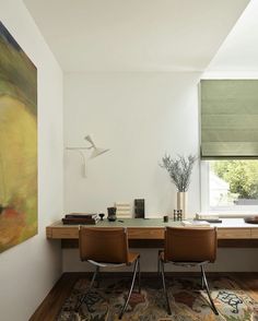 two brown chairs sitting at a desk in front of a window