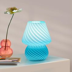 a blue vase with a flower in it next to a pink vase on a table