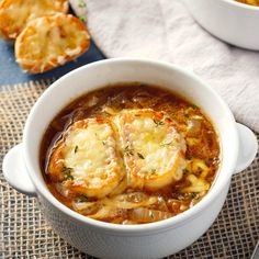 a white bowl filled with soup next to two small pies on top of a table