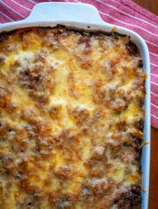 a casserole dish with meat and cheese in it on a red and white towel