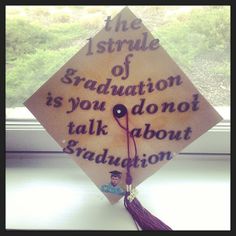 a graduation cap with writing on it and a tassel hanging from the side, in front of a window