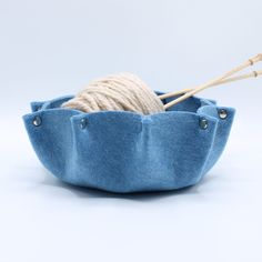 a blue basket with yarn and knitting needles in it