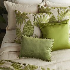 a bed topped with lots of green pillows