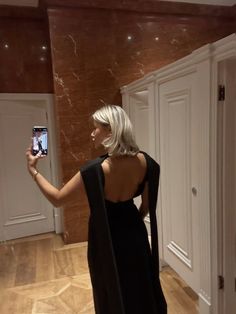 a woman in a black dress taking a selfie