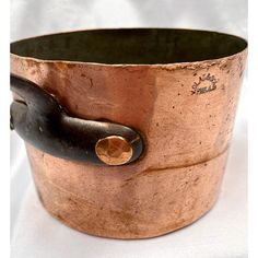 an old copper pot with a black handle