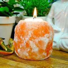 a candle that is sitting on a table next to a statue and potted plant