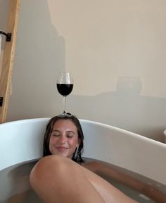 a woman sitting in a bathtub with a glass of wine