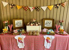 a red and white checkered table cloth topped with donuts next to framed pictures