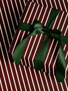 a gift wrapped in brown and white striped paper with a green ribbon on it's side