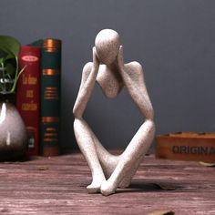 a white statue sitting on top of a wooden table next to books and a vase