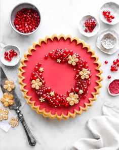 a tart decorated with red berries and gold flowers on top of a white table