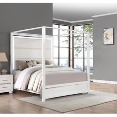 a white bed sitting in a bedroom on top of a hard wood floor next to a window