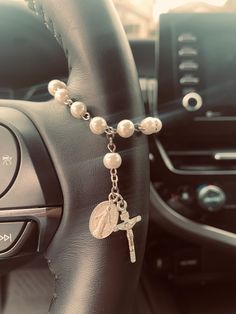 a car steering wheel with a rosary and cross charm on it's link bracelet