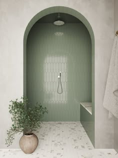 a bathroom with a green wall and white tile flooring next to a potted plant