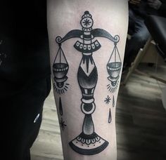 a black and white photo of a lady justice scale tattoo on the right arm, with scales in between them