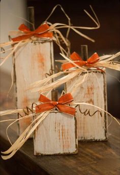 three wooden blocks tied with twine and bows on top of a wood table next to each other