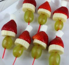 grapes and strawberries wrapped in santa's hats are on a plate with toothpicks