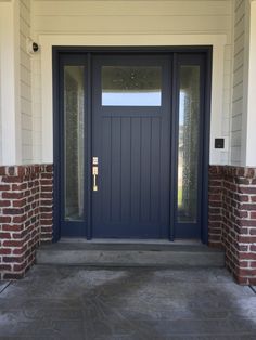 a blue front door with brick pillars and glass panels on the side of a house