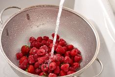 fresh raspberries being washed in a strainer