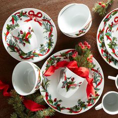 a table topped with plates and cups filled with christmas decorations on top of a wooden table