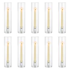 eight candles in glass vases with one lit